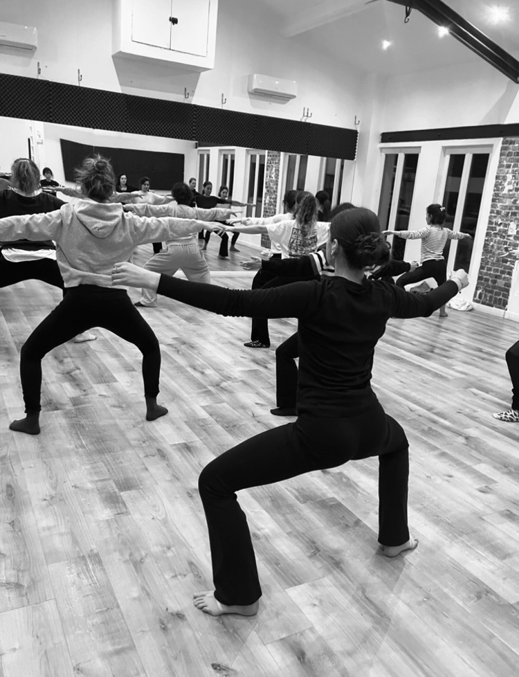 Cours de danse adultes Fusion Modern Jazz : échauffement en groupe, bras tendus, dans le studio de Mishell à Paris